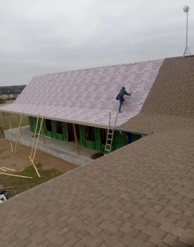 Worker preparing underlayment for a metal roof installation in Geneseo